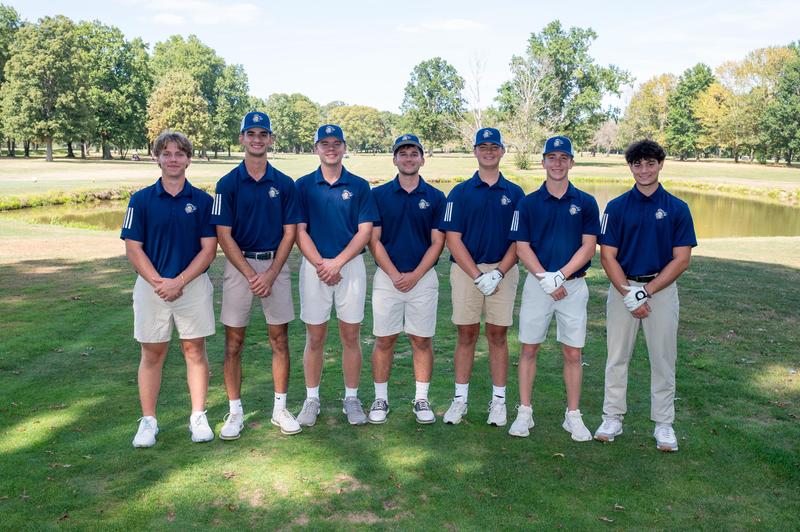 pic of 7 male golfers standing in a grassy area.