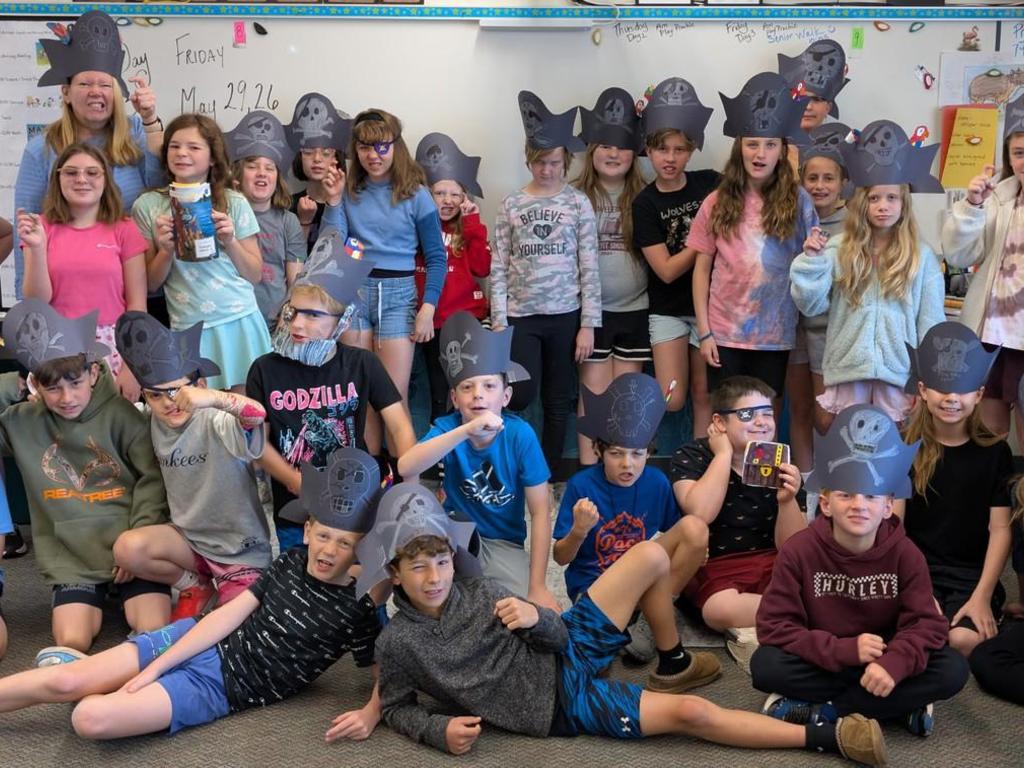 A group of elementary students and their teacher wearing pirate hats that they made.