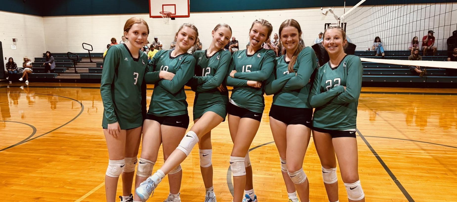The volleyball team poses after a win.