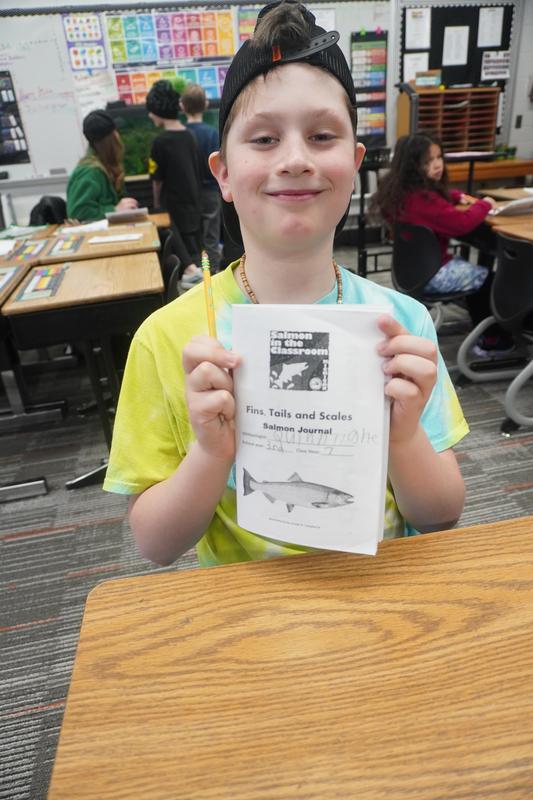 A student holds up his weekly observation booklet.