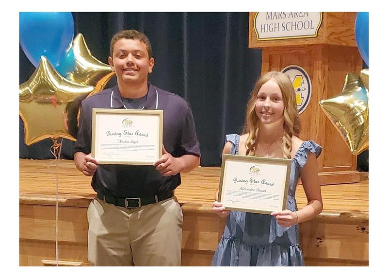 Two students holding certificates at a school award ceremony.