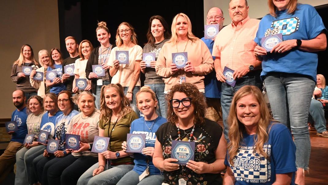 Group of people smiling and holding awards on stage.