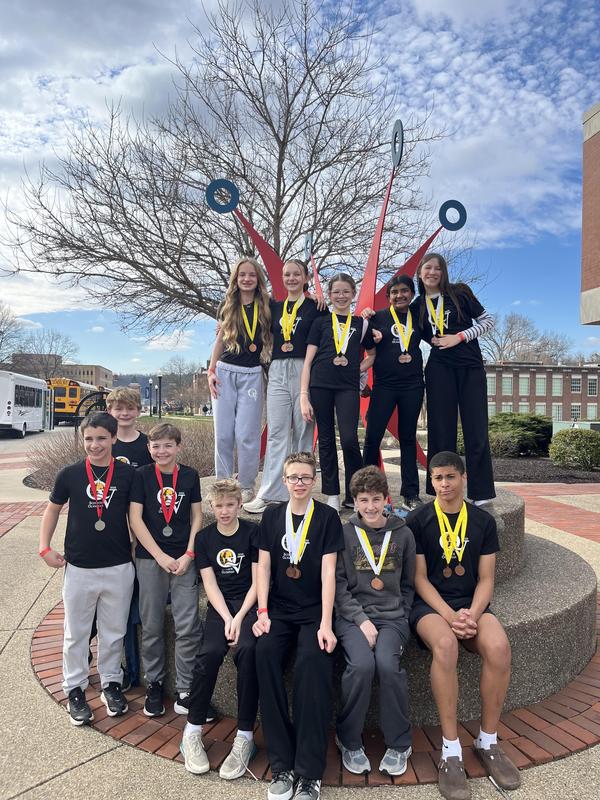 Image depicts a large group of students smiling with medals around their necks.