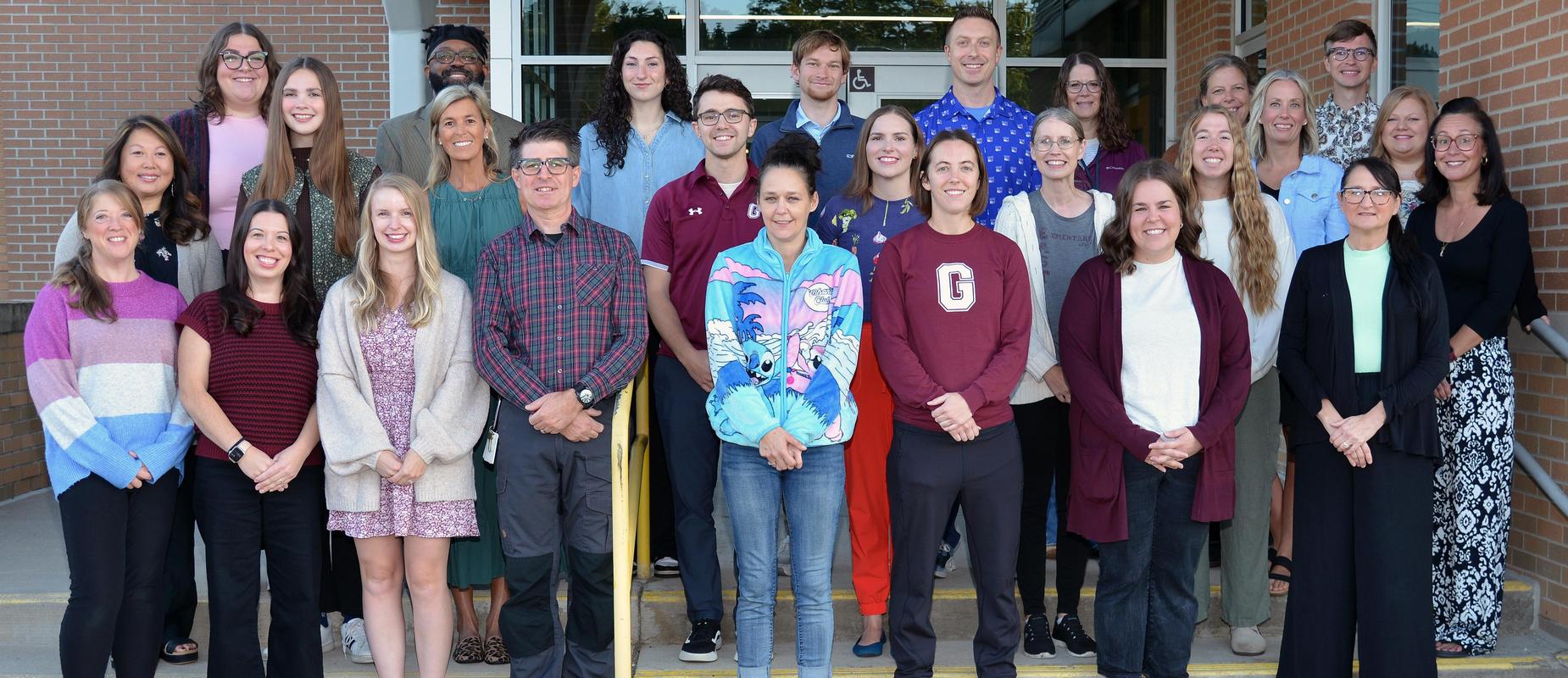 group staff photo in front of building doors in three rows