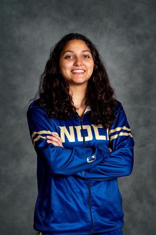 girl in wrestling warm up with curly hair smiling at camera