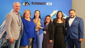 A group of people smiling, one holding an award