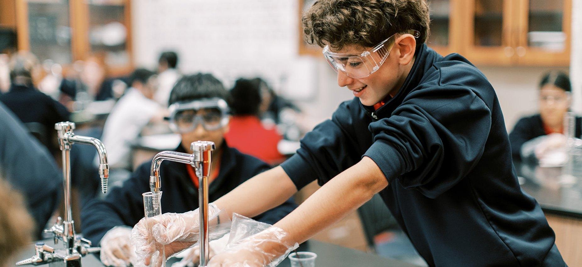 Upper school student in safety goggles working in the science lab at Founders Classical Academy of Corinth
