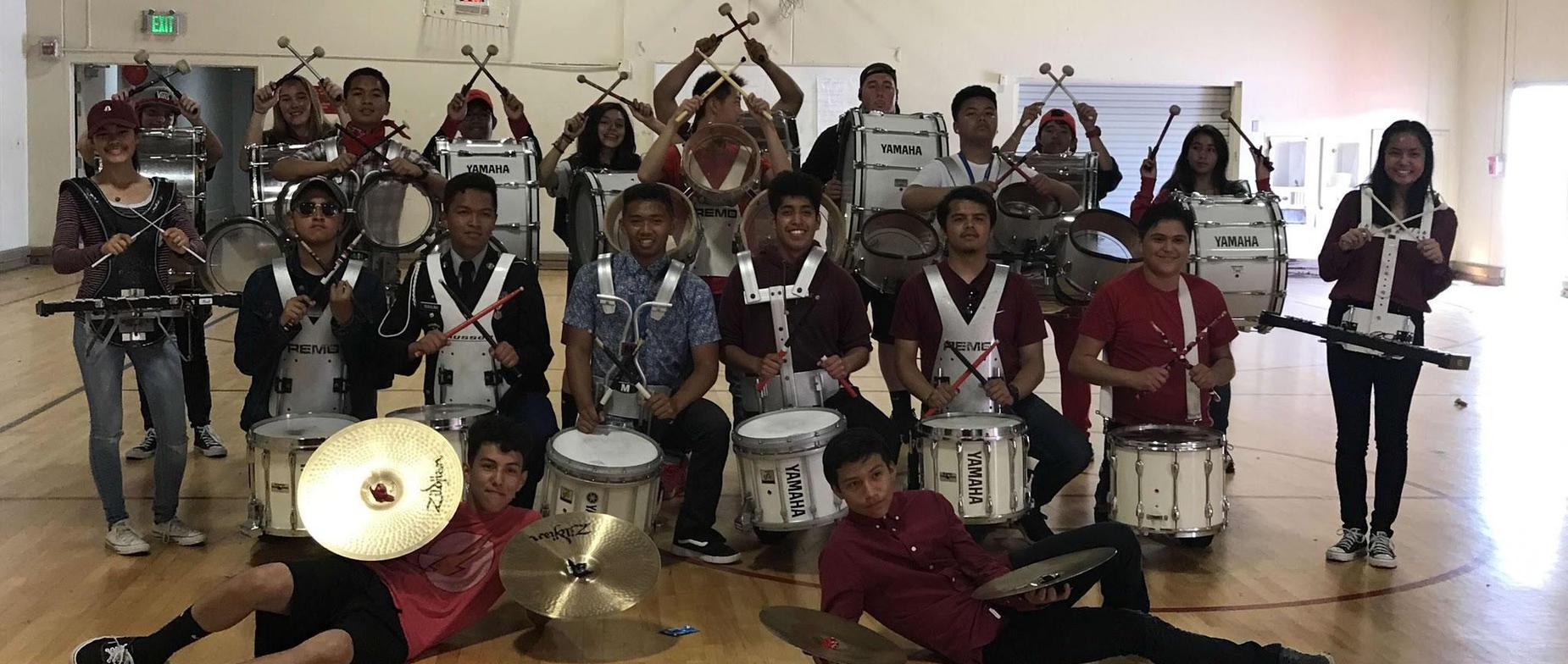 about 30 Seaside High School drum line students both male and female posing for a picture with their drum line gear