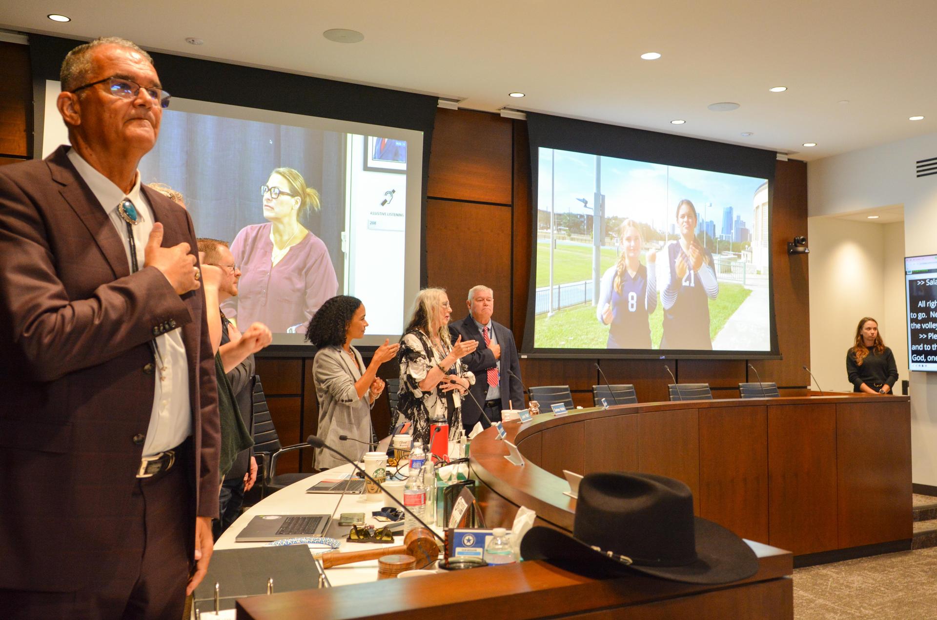 Board members recite pledges with volleyball players on screen.