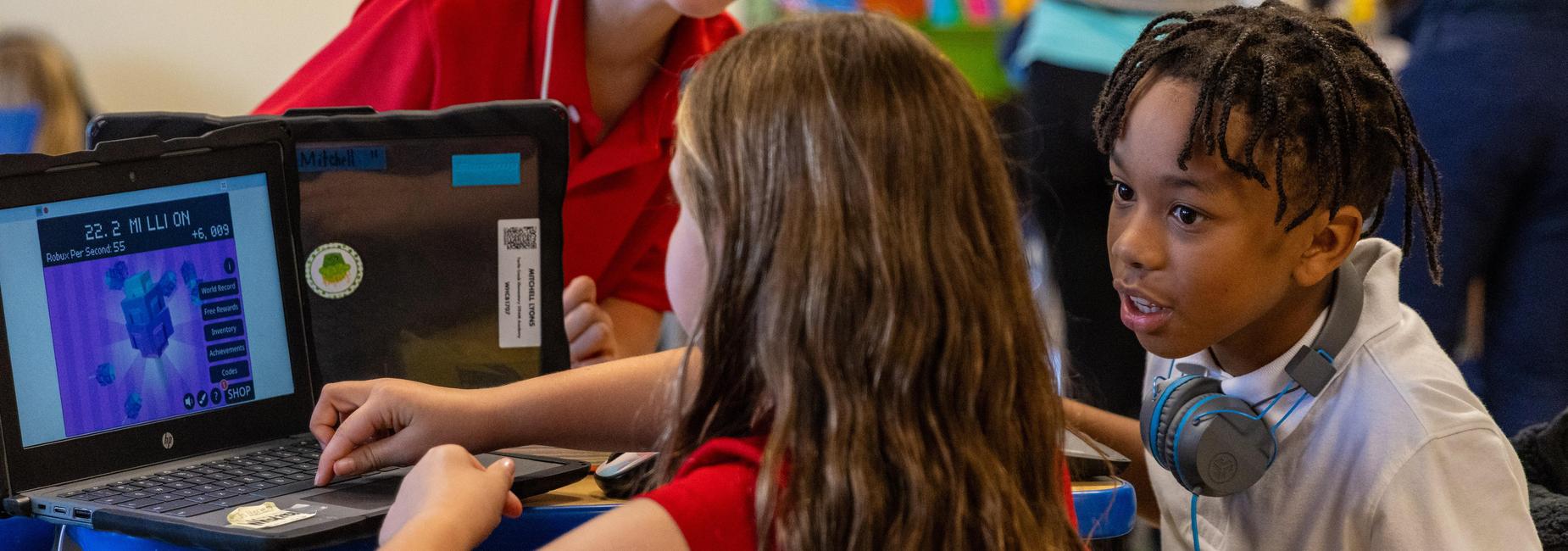 Students play an educational game on a laptop