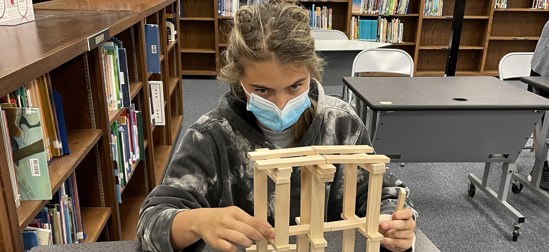 A student works with blocks in a library.