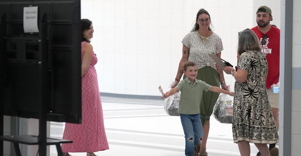 A student runs to hug a teacher in a hallway