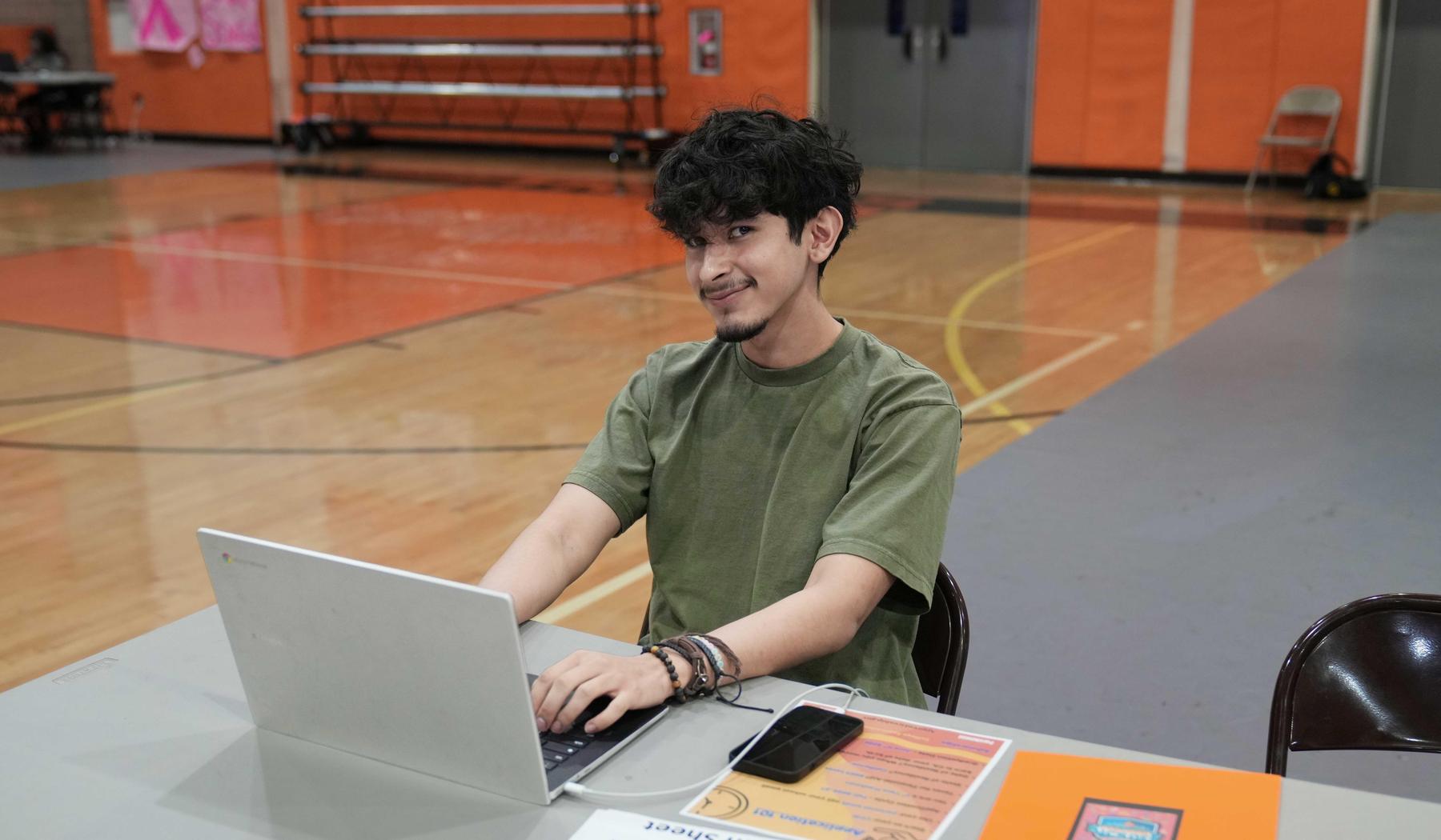 Smiling high school boy working on laptop computer