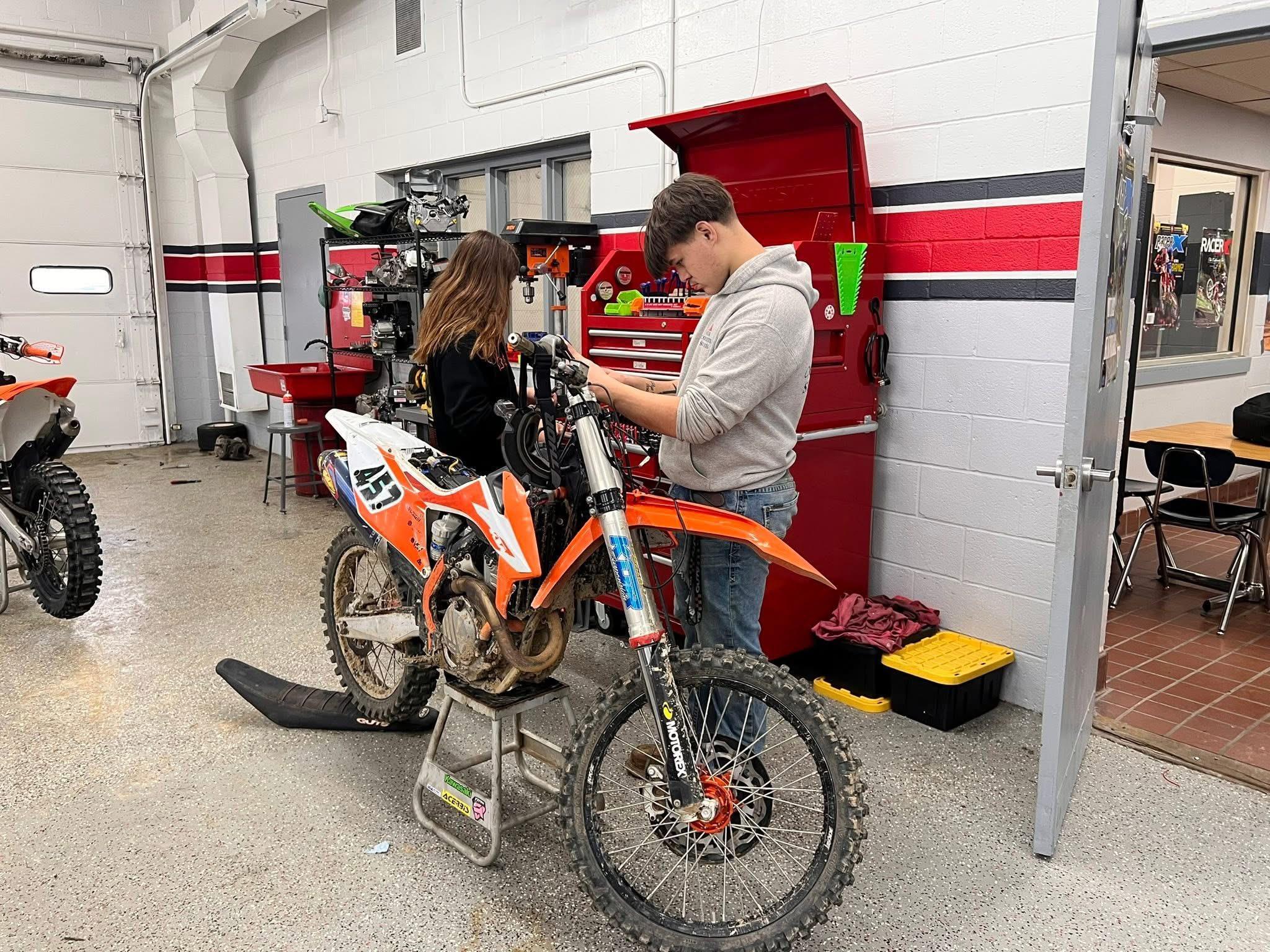 A students working on a motorcycle.