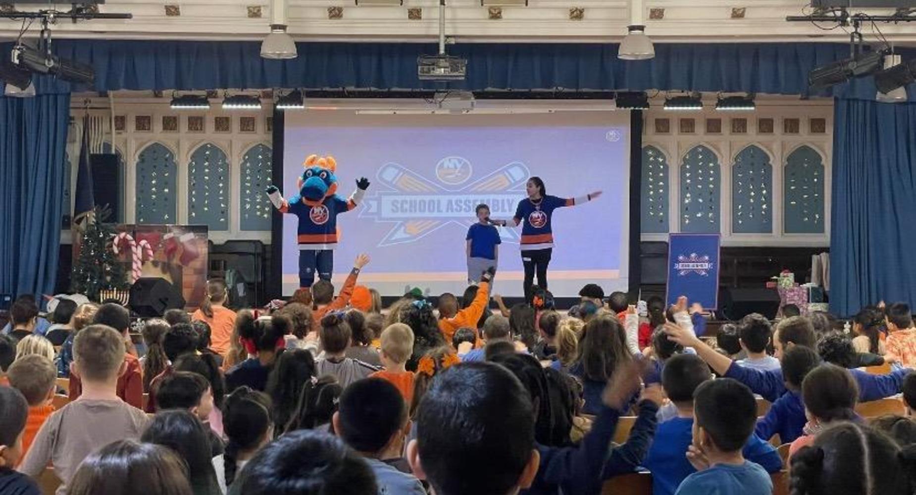 NY Islanders assembly with Islanders' mascot, speaker and a student on the stage