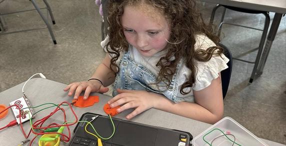 young students at work on laptop using brightly colored cords on desk