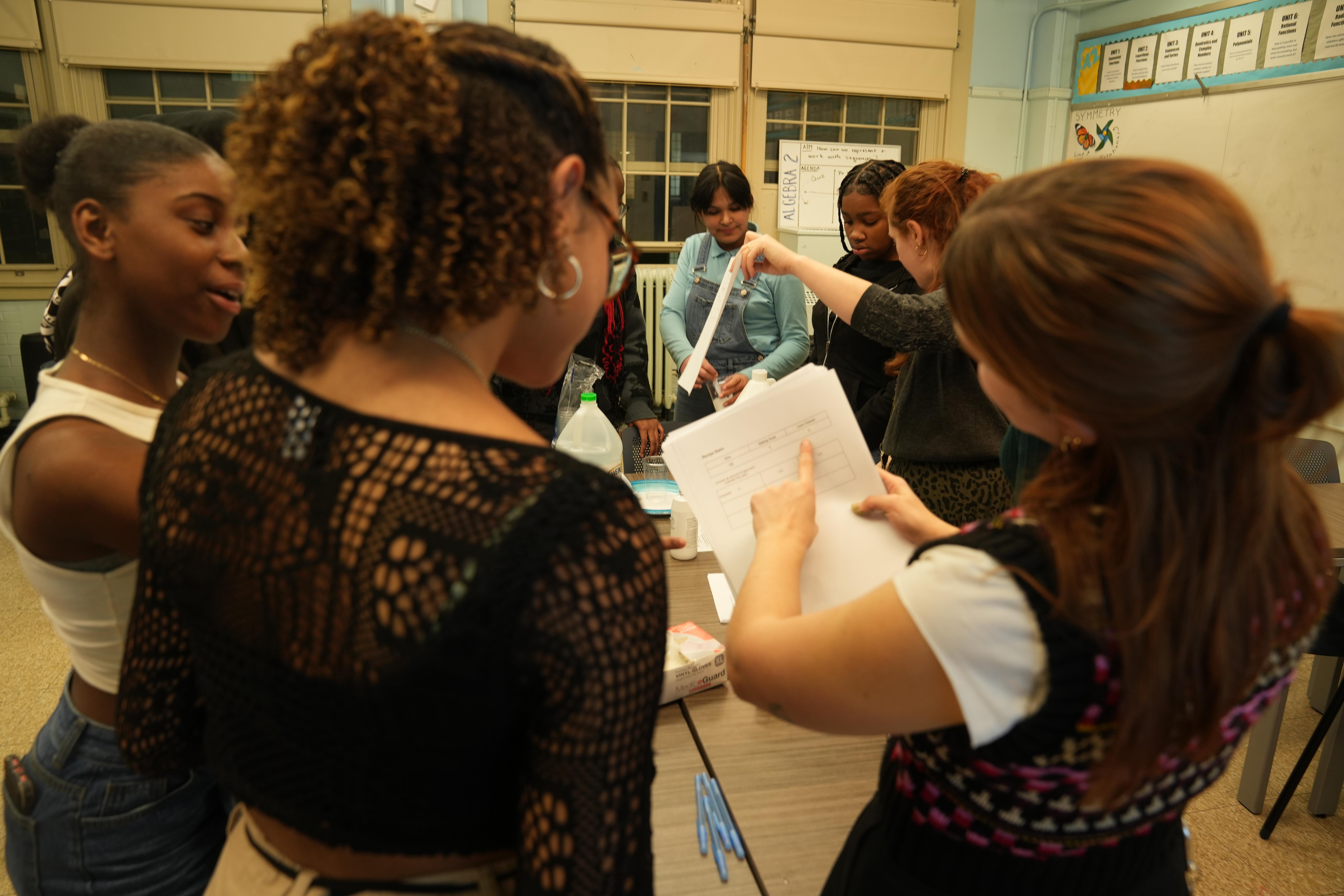 two girls, one with short curly hair, and one with straight red hair looking at a paper