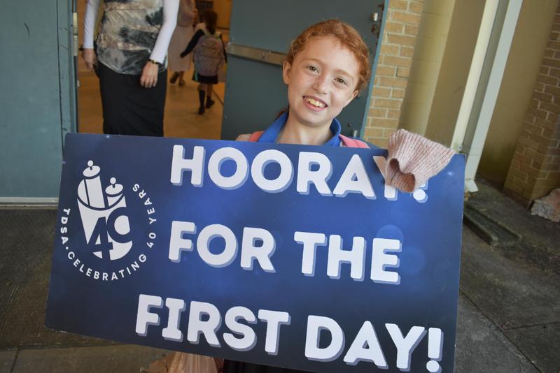 A third grader poses with a first day of school sign