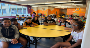 Alumni sitting at yellow table in cafe.