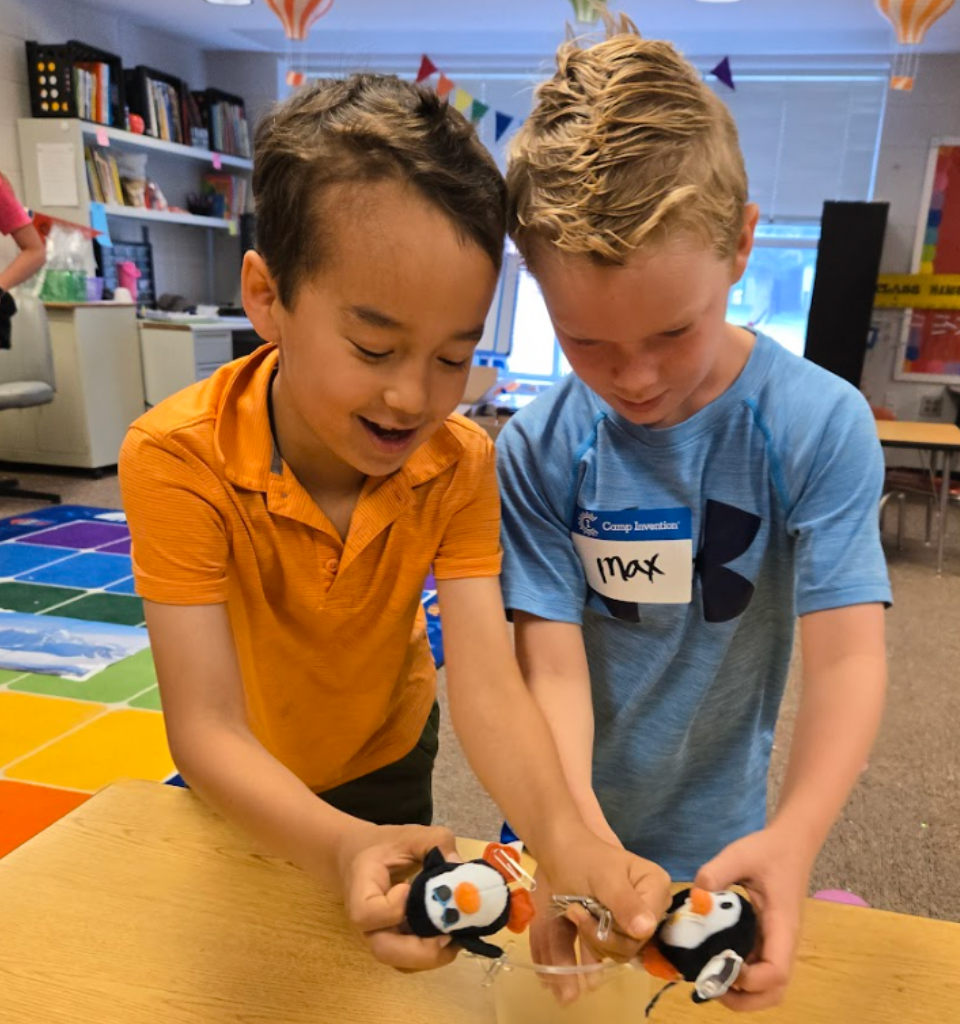 Two boys joyfully holding stuffed puffins in a classroom.
