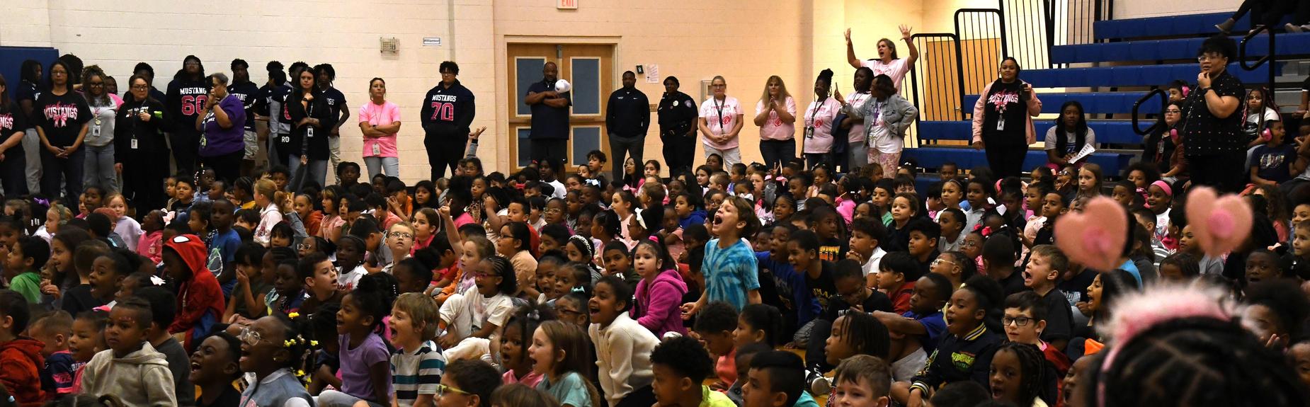 A large crowd of children seated on the floor, attentively participating in an event.