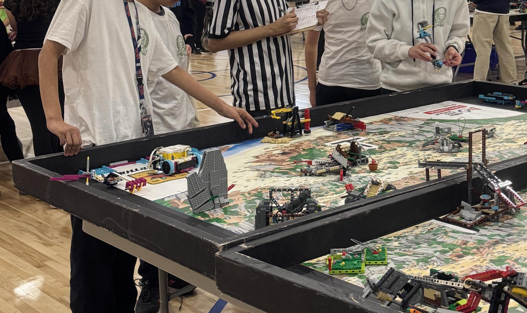 Four boys at First Lego League competition table with mission table.