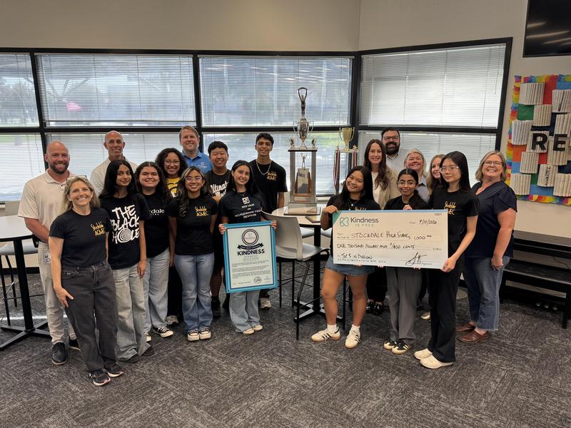 Stockdale Academic Decathlon team is presented with a plaque and check inside the school library.