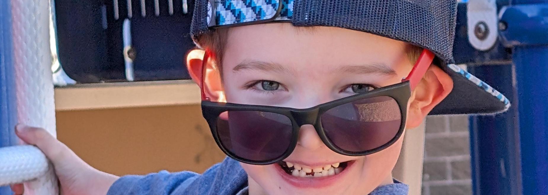 Smiling child in sunglasses on a playground.