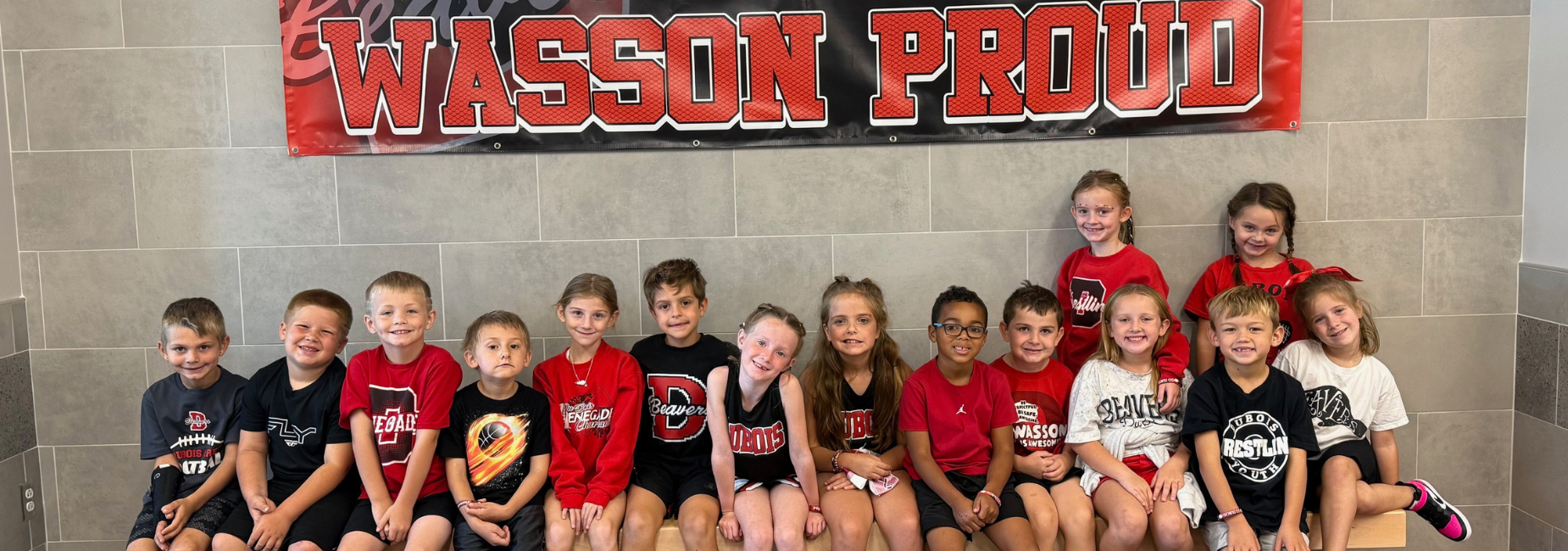 Large group of kids in matching shirts posing in a hallway.