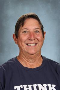Smiling woman with short hair in a t-shirt, against a light background.