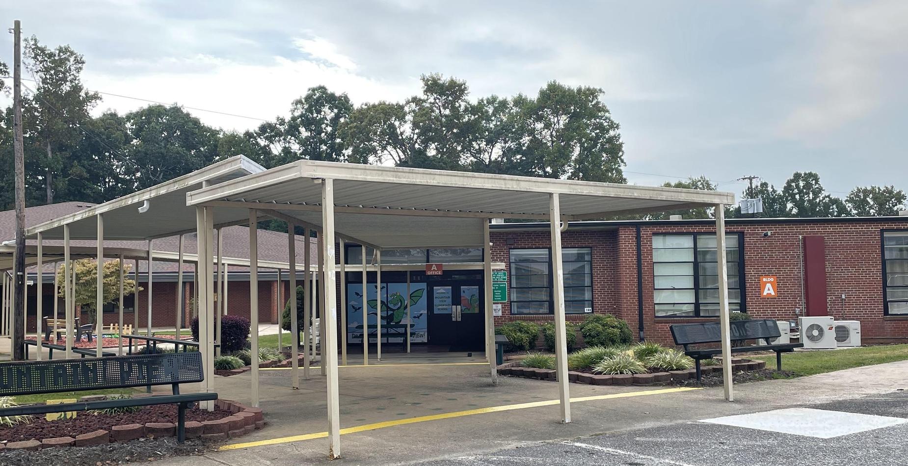 Entrance of a school building with a covered walkway and benches.