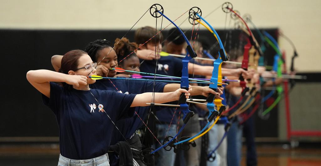 A line of student archers takes aim