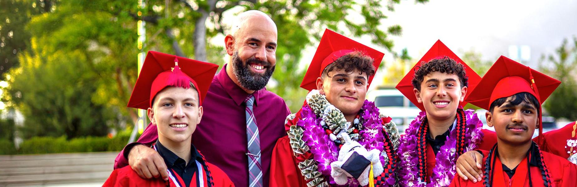 Group of five high school graduates in caps and gowns, smiling with a teacher at Alta Loma Christian School.