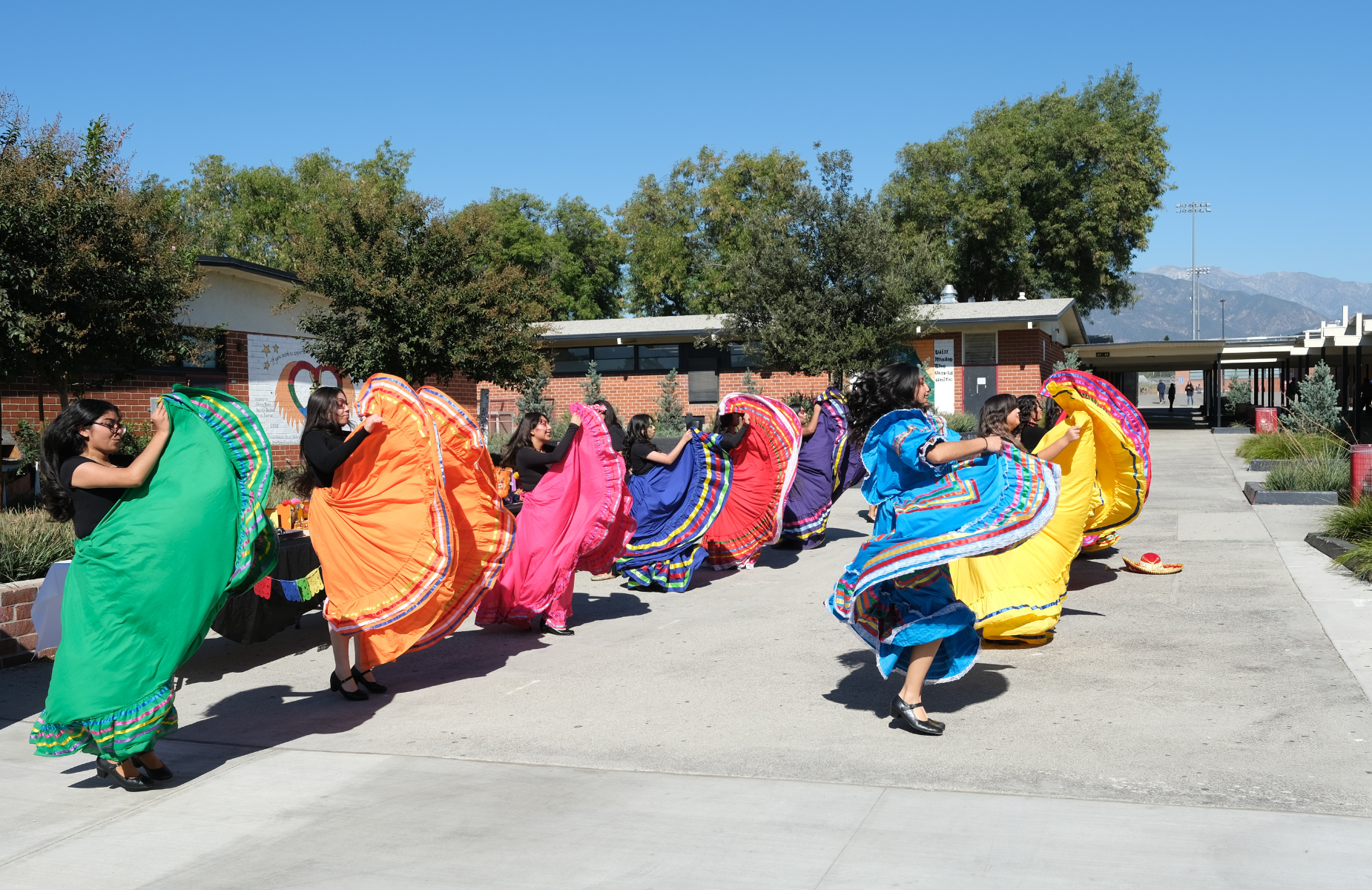 Shuffle banner for district homepage - infographic of students dancing Folklorico with bright dresses from Pomona High School