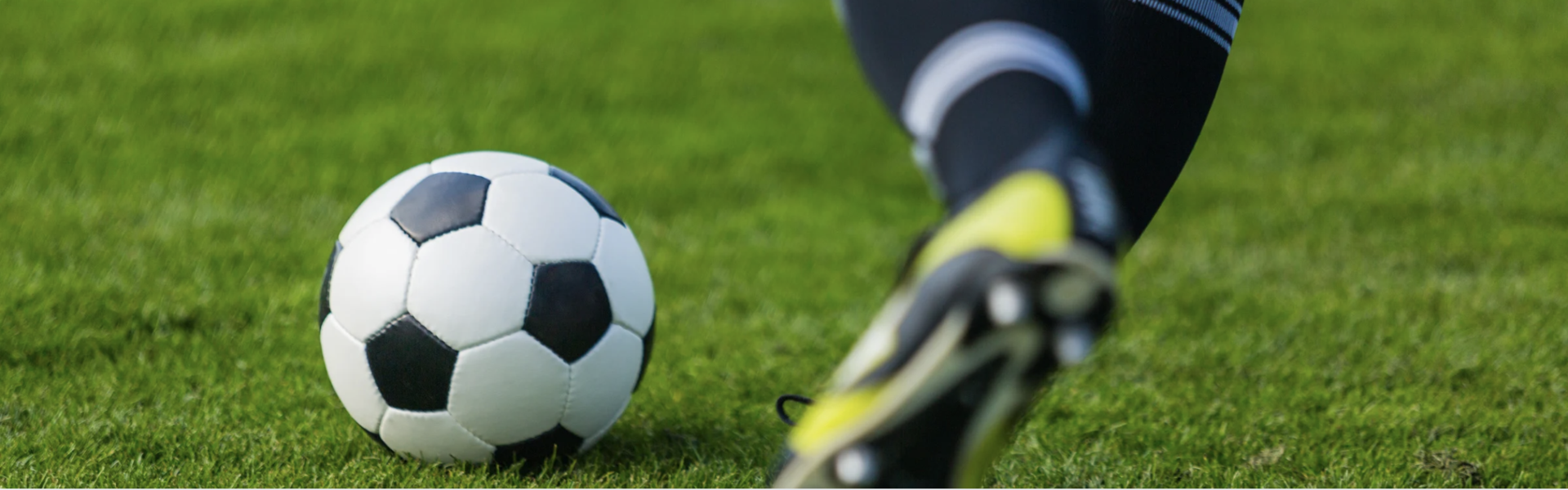 A soccer player wearing cleats about to kick a ball