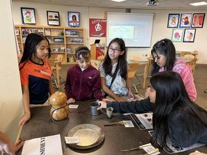 four girls looking at historical artifacts on a table