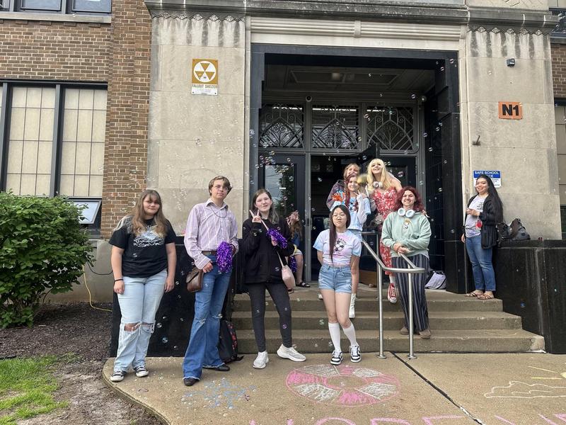 Students standing on steps outside, surrounded by bubbles and decorations.