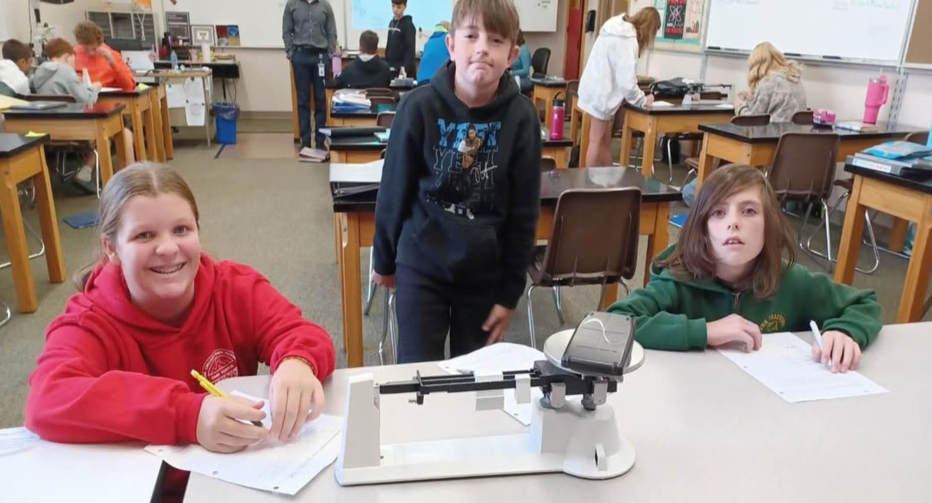 Penn Middle students use a scale in class to weigh an object