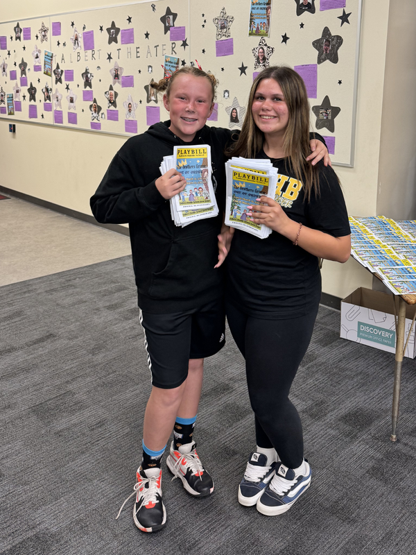 Two students holding Playbills for the Brother's Grimm Play