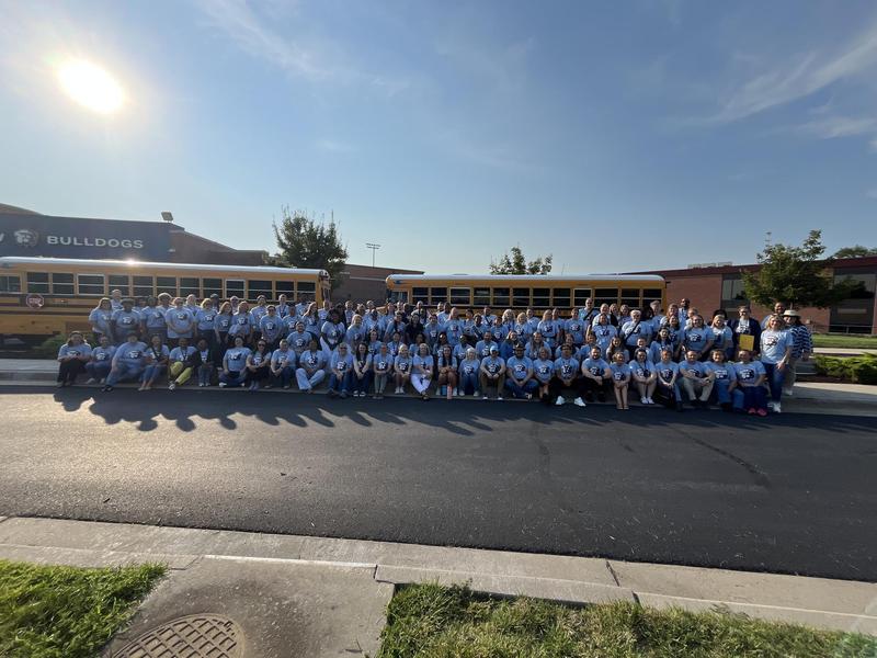 new staff lined up in front of a school bus