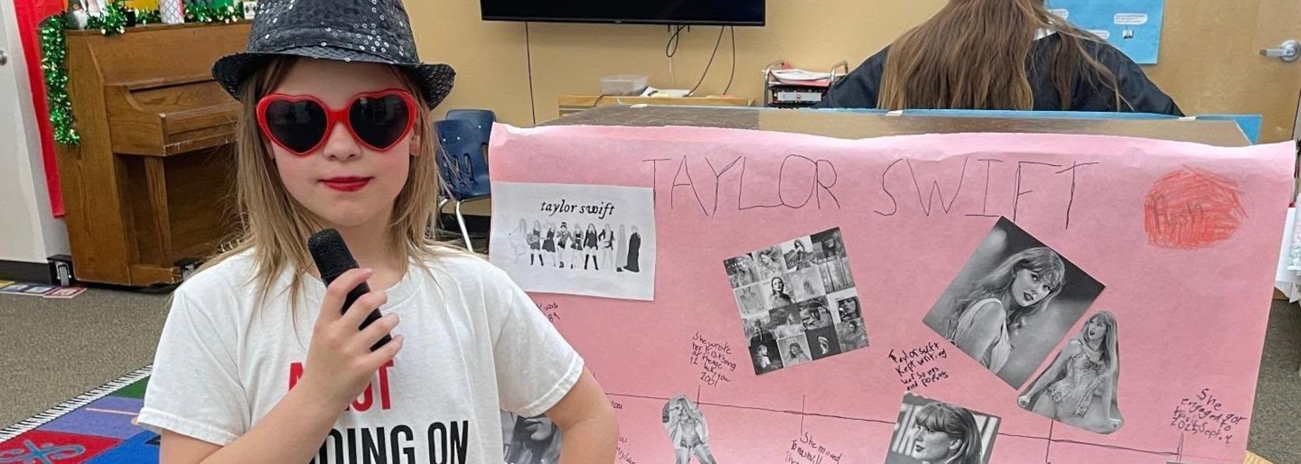 Child in a white shirt poses next to a display board with photos.