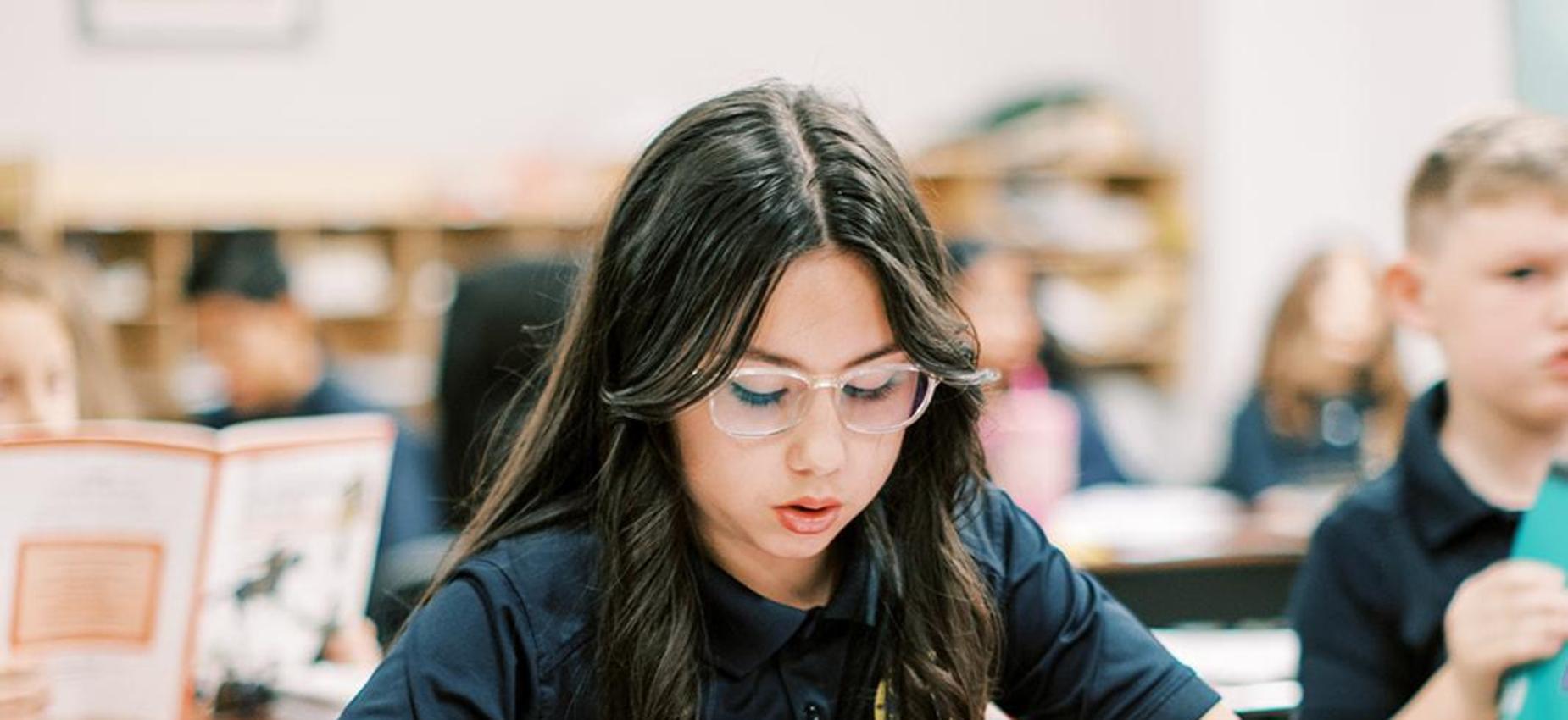 Middle school student reads a book at her desk