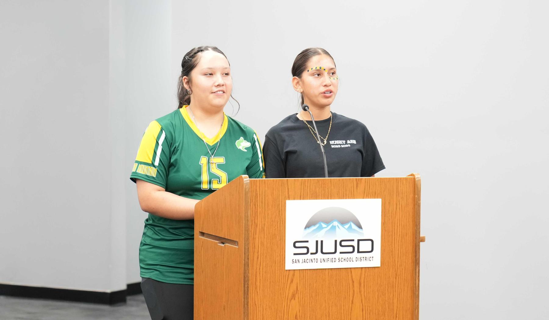 two students giving a report to the Board of Trustees