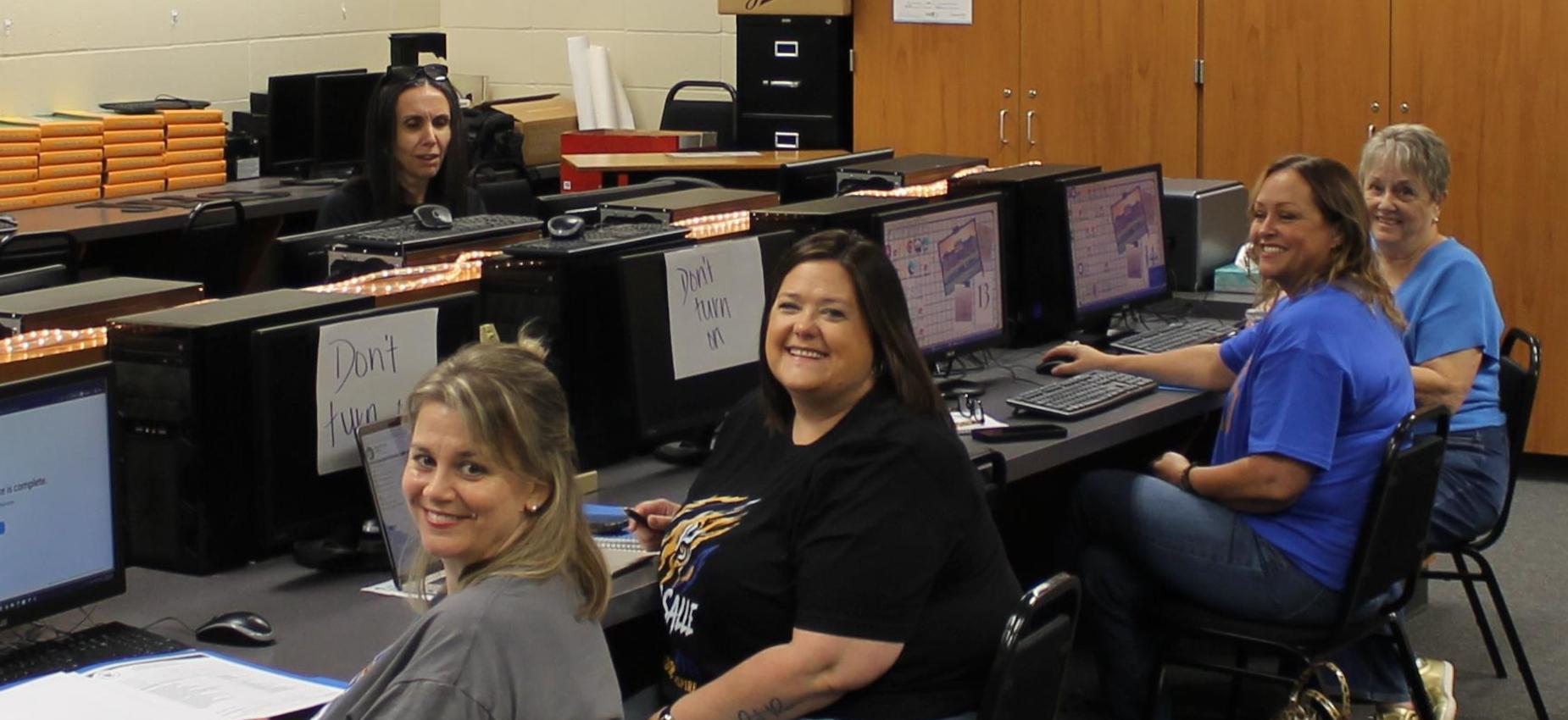 A group of people in a computer lab, sitting at desks and using computers.
