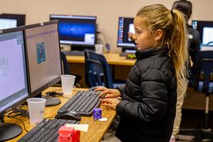 Child working at a computer in a classroom setting.