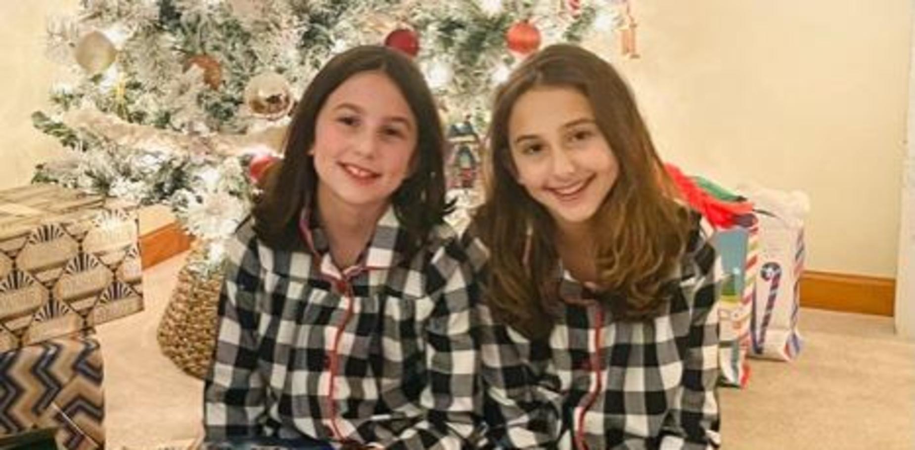 two girls in holiday attire in front of a tree
