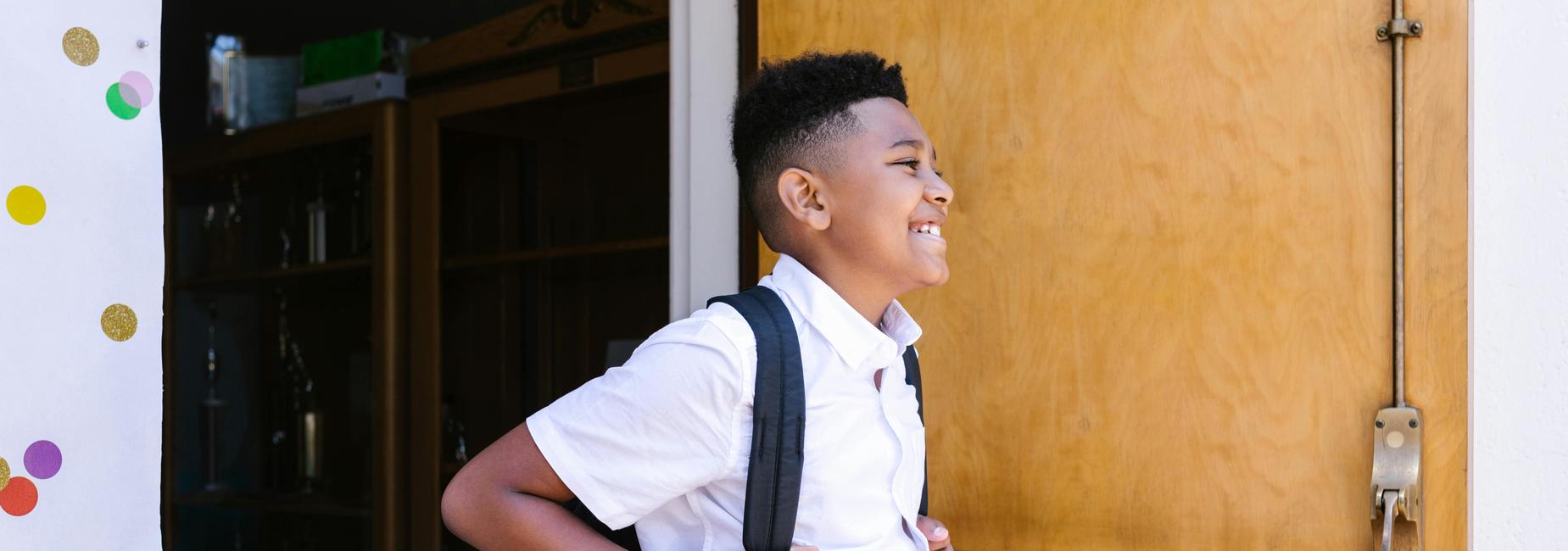 student smiling walking out of school building