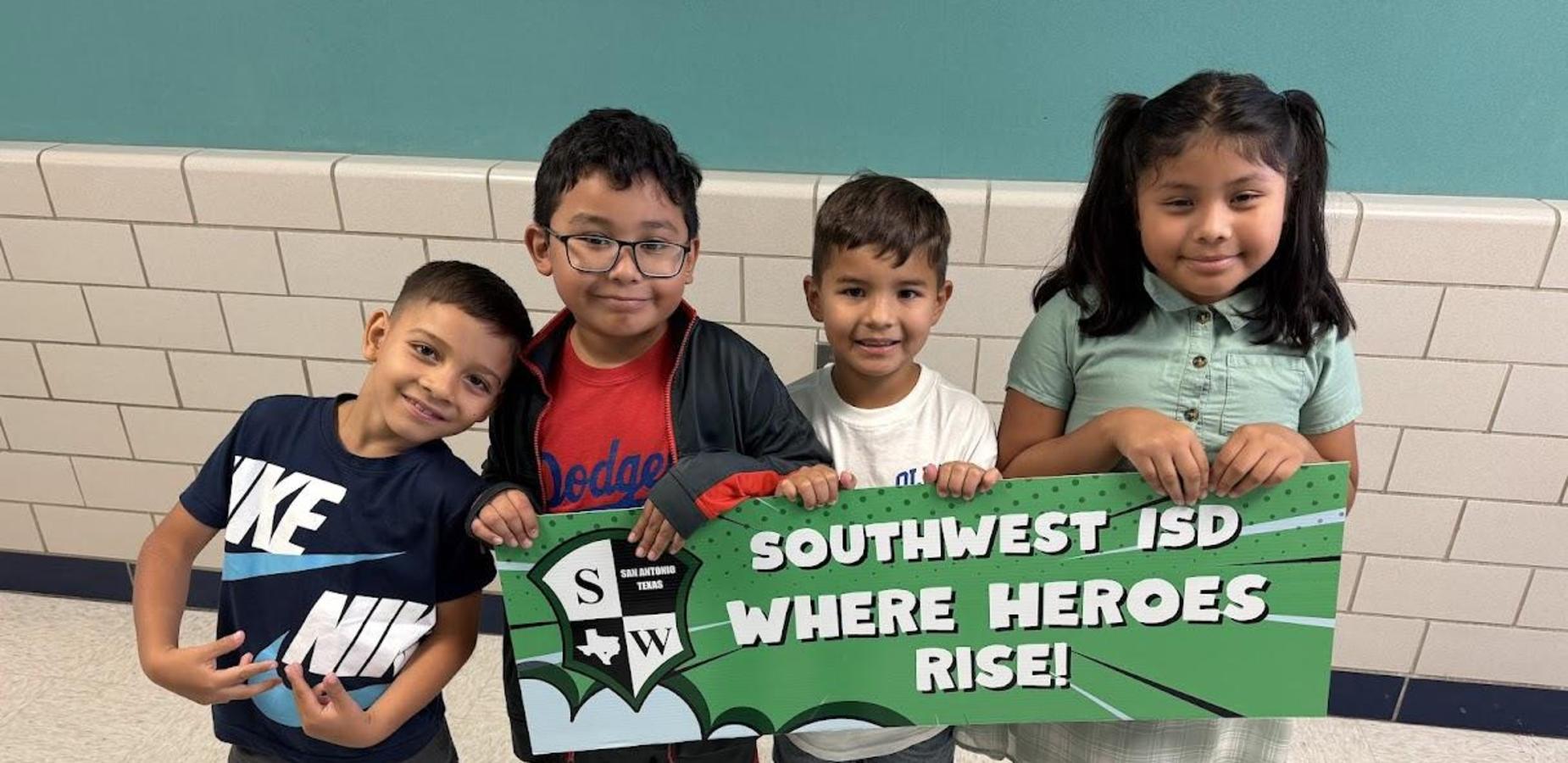 Three boys and one girl holding green and white SW sign