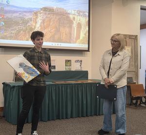 student showing off bird drawing while announcer of scholarship looks on