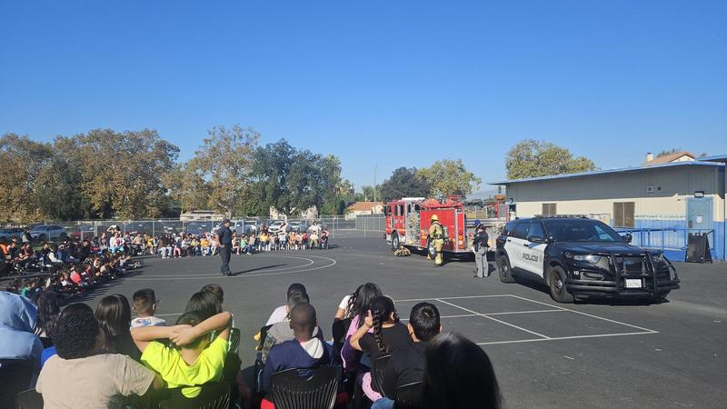 firefighters talk to students during assembly on a blue sky at the basketball courts